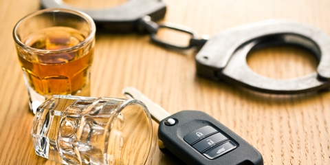 Car keys next to empty shot glass, with handcuffs in background